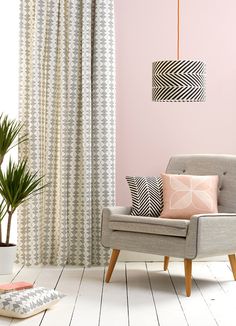 a living room with pink walls and white flooring, a grey chair in the foreground