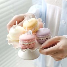 a person holding a plate with three macaroons on it