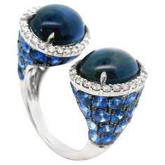 A unique and stylish ring in an open modern style. It features two large cabochon sapphires along with round blue sapphires weighing a total of 17.34 carats. It is accented by 0.72 carats of round brilliant-cut diamonds which add brilliance and sparkle to the piece. Made in 18k white gold and ready to be worn. Ring Size 6.50 Weight: 11.6 grams Luxury Sapphire Open Ring Jewelry, Stylish Rings, Blue Sapphire Diamond, White Gold Diamond Rings, Sapphire Diamond Ring, Gold Band Ring, Modern Ring, White Gold Band, Sapphire Stone