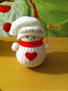 a small snowman with a hat and scarf on it's head holding a sign that says i love you