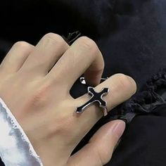 a person wearing a ring with a cross on it's middle finger and black satin