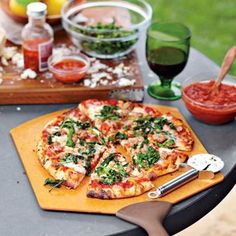 a pizza sitting on top of a wooden cutting board next to a table filled with food