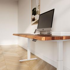 a computer monitor sitting on top of a wooden desk next to a white framed wall