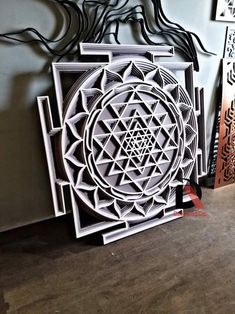 an intricately designed paper sculpture on display in a room with wood flooring and wall hangings