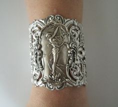 "Art Nouveau Bracelet This beautiful silver plated cuff bracelet has a silver plated art nouveau maiden, silver plated chain and lobster clasp. 2.75\" at the widest part. 7\" long adjustable to 9\" long." Unique Antique Silver Bracelets For Formal Occasions, Victorian Sterling Silver Bracelets In Antique Silver, Handmade Victorian Cuff Bracelet For Wedding, Art Deco Bracelets With Intricate Design As Gift, Ornate Antique Silver Cuff Bracelet For Weddings, Victorian Silver Bracelets For Wedding, Elegant Antique Silver Cuff Bracelet, Victorian Silver Wedding Bracelets, Elegant Sterling Silver Cuff Bracelet For Collectors