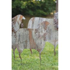 two metal sheep sculptures sitting in the grass