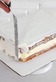 a person cutting a cake with a knife on top of the cake and white frosting