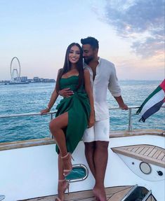 a man and woman standing on the deck of a boat in front of the ocean