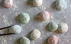 several different colored powdered doughnuts on a baking sheet with a pair of scissors