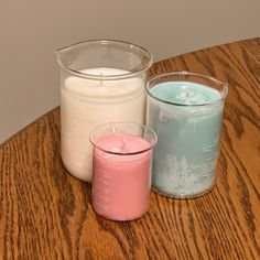 three different colored candles sitting on top of a wooden table