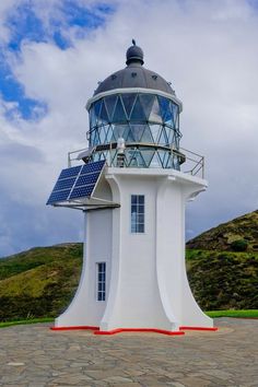 a white lighthouse with a solar panel on top