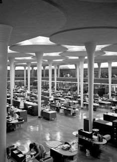 the interior of an office building with columns and desks in black and white photo