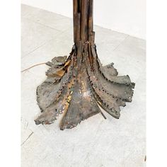 a tall wooden table topped with lots of leafy metal pieces on top of a white tile floor