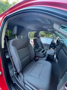 the interior of a red car with its door open and seats folded down in front of it