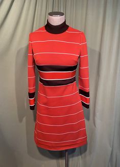 "This is a cute vintage dress from the 70s. Label reads, Verona Knits. No size tags. The bust measures 32\", waist 30\", see measurements below. Made of a rust orange, brown & white horizontal stripe polyester knit. It has long sleeves & a mock turtle neck. The rust orange stripes inside the dark brown stripes at the waist on the sleeves & a slightly thicker knit. The dress is skims the body & it is not lined. The sleeves are wrist length. The neckline is fold over mock turtleneck. Zips in the b Retro A-line Vintage Dress For Fall, Retro Fitted Vintage Dress For Winter, Retro Mini Length Fall Dresses, Vintage Orange A-line Dress, Fitted Retro Vintage Dress For Fall, Fitted Retro Vintage Dress For Winter, Retro Long Sleeve Mini Dress For Fall, Fall Retro Long Sleeve Mini Dress, Retro Long Sleeve Fitted Dress