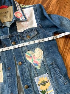 an old jean jacket with patches on it and a measuring tape in front of it