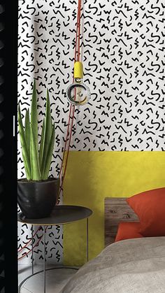 a bedroom with yellow, black and white wallpaper next to a small round table