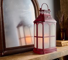 a red lantern sitting on top of a mantle next to a mirror