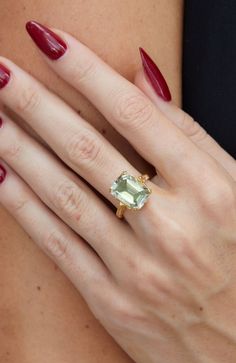 a woman's hand wearing a ring with an oval shaped green stone on it