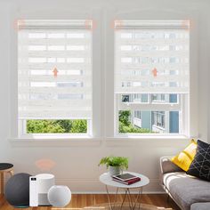 a living room with two large windows and a table in front of the window that has a book on it