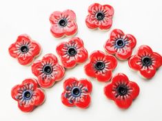 red flowers with black centers sitting on a white surface