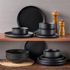 black plates and bowls are sitting on a shelf