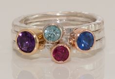 Hand fabricated Stacking Family Rings in Sterling Silver and 18k gold with genuine gemstones. This is an example of one custom order Stacking Family ring that I made using genuine natural earth mined Amethyst, Blue Zircon, Ruby and Sapphire. They are bezel set in 18k rose, yellow and white gold bezels. The shanks are made from Sterling Silver which helps them be more affordable. The Ruby was the most expensive of all the gems used. The price for this set as is is $2300.00 Canadian. To get a quote for your custom hand fabricated Staking family ring please make a custom order inquiry mentioning all the birthdays. you want included in your rings. Because these are hand fabricated they are up to 10 times more durable than cast jewelry. The quality of bezels are so good they will not wear down Anniversary Fine Jewelry Gemstones With Bezel Setting, Anniversary Gemstones With Bezel Setting In Fine Jewelry Style, Anniversary Gemstones With Bezel Setting, Fusion Style Birthstone Jewelry For Anniversary, Anniversary Multi-stone Round Gemstones, Fine Jewelry Stackable Rings With Gemstone Accents, Sapphire Ring With Gemstone Accents For Anniversary, Round Sapphire Ring With Gemstone Accents For Anniversary, Gold Fusion Style Birthstone Gemstones