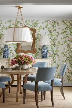 a dining room with floral wallpaper and blue chairs