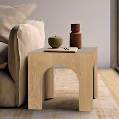 a wooden table with a vase on it next to a couch and window sill