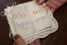 a person holding a small box with some pins and needles in it on a wooden table