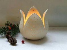 a white ceramic candle holder sitting next to pine cones