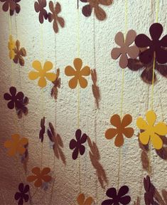 paper flowers hanging from strings on a wall