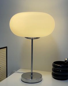 a lamp sitting on top of a white table next to a black plate and bowl