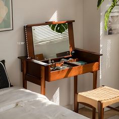 a bedroom with a bed, desk and mirror in it's corner area next to a plant