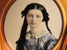 an old photo of a woman with braids on her hair in a gold frame