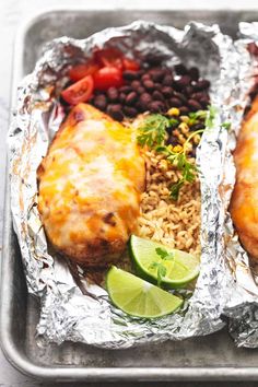 chicken, rice and beans on tin foil with lime wedges