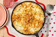 a casserole dish with cheese and onions on a red and white tablecloth