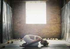 a woman is doing yoga in an empty room with sunlight coming through the window and floor