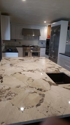 a kitchen with marble counter tops and stainless steel appliances in the backround area