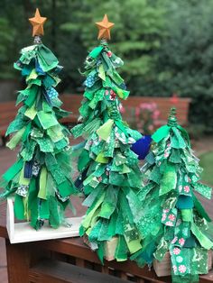 two paper christmas trees sitting on top of a wooden table