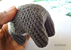 a hand is holding a small crocheted hat