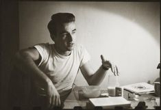 black and white photograph of a man sitting at a desk with his hand in the air