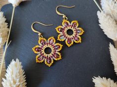 a pair of yellow and red beaded earrings sitting on top of a black surface