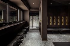 a bathroom with black walls and stools in front of the sinks, mirrors and shower