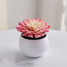 a white vase with a pink flower in it