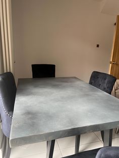 a table and chairs in a room with white tile flooring on the walls, along with a black leather chair