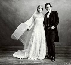 black and white photo of bride and groom posing for wedding portrait with veil blowing in wind