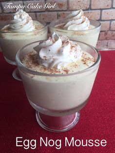 egg nog mousse with whipped cream in a glass dish on a red table