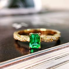 an emerald colored ring sitting on top of a book