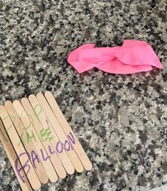 some wooden sticks with writing on them and a pink bow laying next to each other